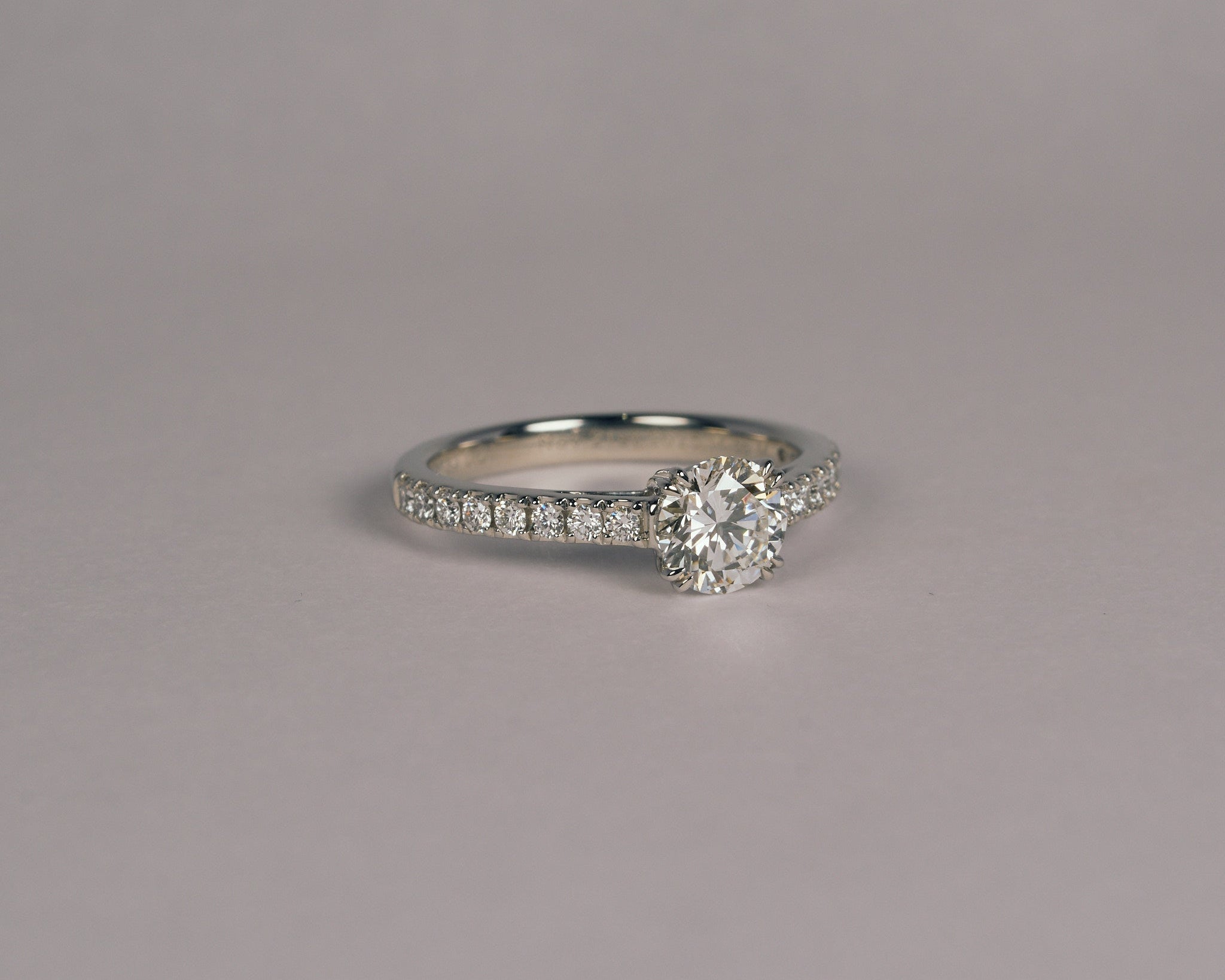 お持ち込みのダイヤモンドをハーフエタニティのアームに留めた、プラチナ950の婚約指輪