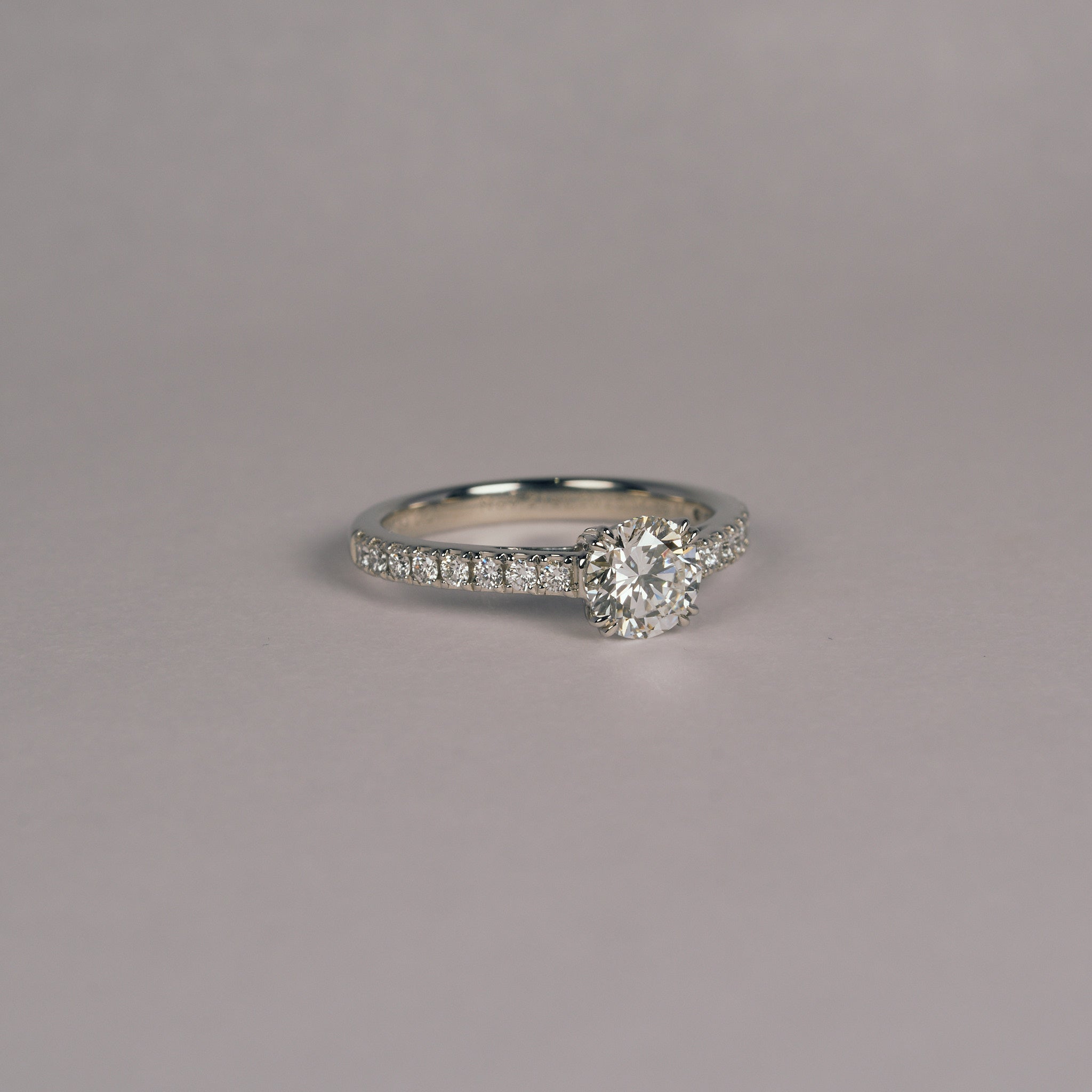 お持ち込みのダイヤモンドをハーフエタニティのアームに留めた、プラチナ950の婚約指輪